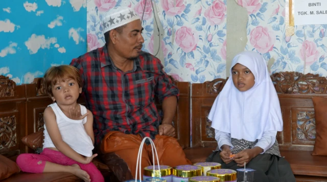 Zaman Huri bersama kedua anaknya di ruang tamu rumahnya.