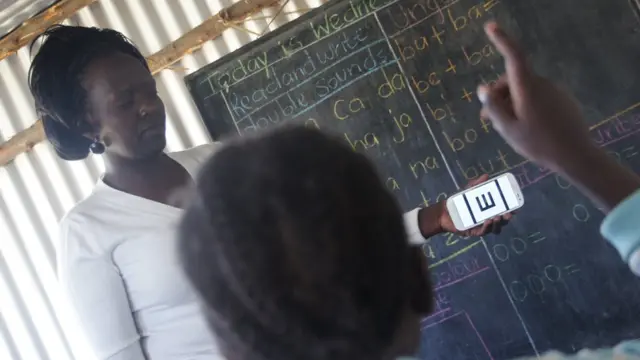 Sawir muujinaya macalimiinta iyo carruurta oo isticmaalaya Teknooloojiyadda