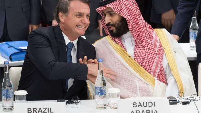 Sentados dianteeleição sportingbetplacas com os nomeseleição sportingbetseus respectivos países, Jair Bolsonaro e Mohammed bin Salman sorriem enquanto apertam as mãos