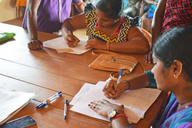 අයැදුම්පත් පුරවන් කාන්තාවන් දෙදෙනෙකු සිටින ඡායාරූපයකි