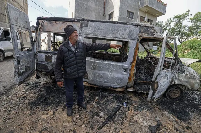 Un hombre junto a un vehículo incendiado en Jalud