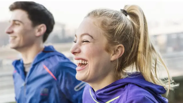 Mujer y hombre corriendo y riendo.