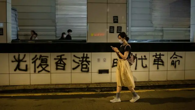 九龙尖沙咀一名女士走过示威者留下的抗议标语涂鸦（3/8/2019）