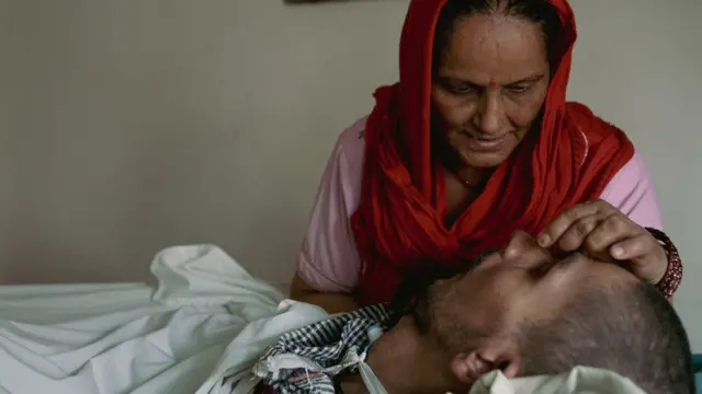 Nirmala Rana u roze majici i crvenom šalu miluje glavu sina Hariša koji je u vegetativnom stanju