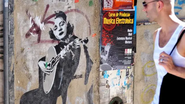 Португальцы чтят память "королевы фаду" Амалии Родригиш - в Лиссабоне есть памятник Родригиш, а на этом фото турист рассматривает граффити с ее изображением