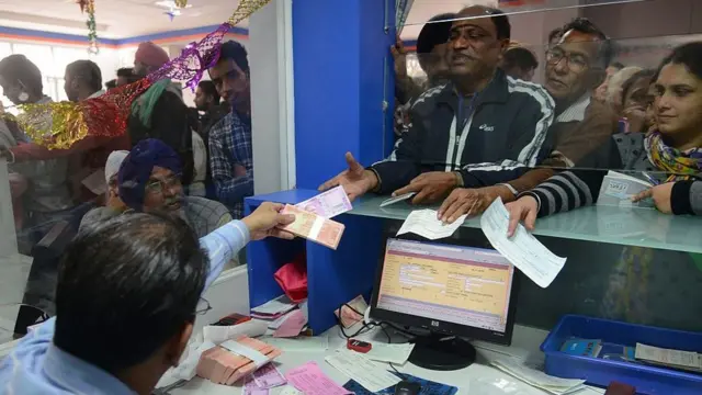 બેંકમાંથી લોકો નાણા ઉપાડી રહ્યા છે તેની તસવીર