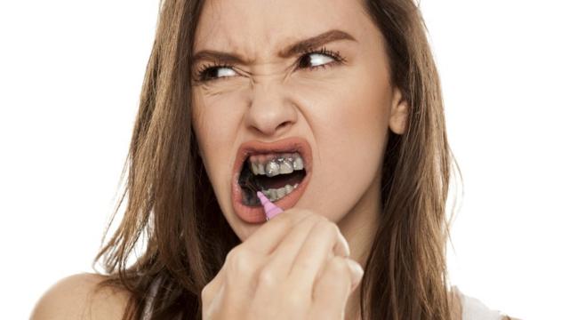 Una mujer se cepilla los dientes con una pasta dental a base de carbón.