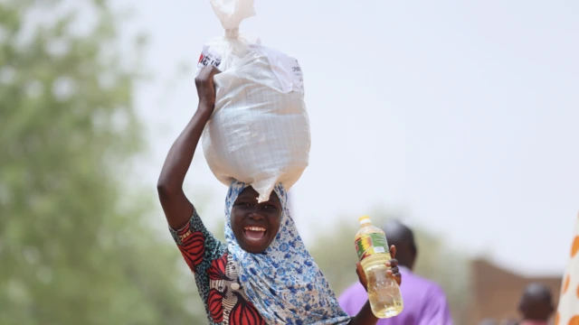 A smiling woman carrying aid supplies in Niamey, Niger - Wednesday 23 March 2022