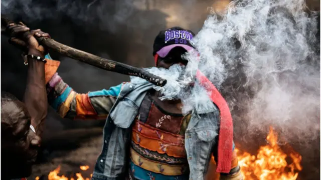 Protester hold stick wey dey burn for street of Kenya