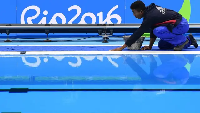 Un trabajador cuida los últimos detalles e la piscina antes del inicio de los juegos.