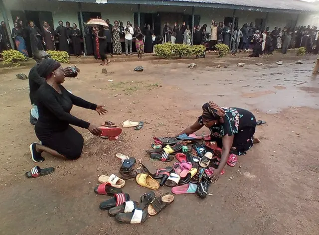 Des parents d'élèves enlevés au lycée Bethel Baptist prient pour qu'ils reviennent sains et saufs autour de chaussures abandonnées par les enfants, à Kaduna, au Nigeria, le 9 juillet 2021.
