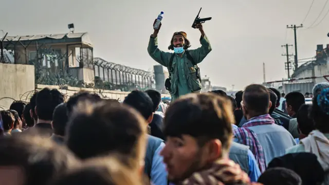 A Taliban fighter keeps Afghans from crossing a checkpoint passage before the road that leads to the military entrance of the airport, in Kabul, Afghanistan, on 19 August 2021