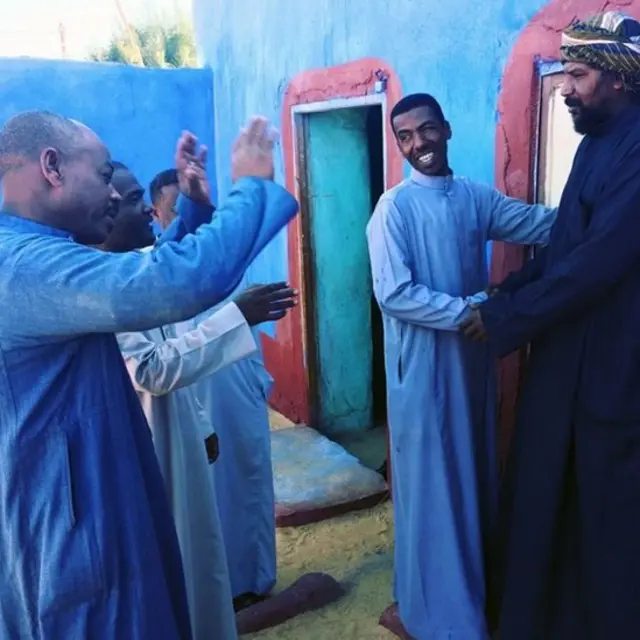 न्यूबियाई पंरपरा की न्योता देने की प्रथा का पालन करते हुए अकरम (बीच में)