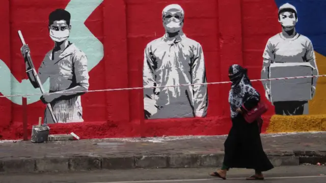 A woman walks past a mural in tribute to frontline workers during the COVID-19 pandemic in Mumbai