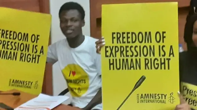 Protesters from Amnesty International carri placard