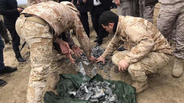 Security forces retrieve debris from a crater reportedly caused by an Iranian missile in Bardah Rashsh, in Iraq's Kurdistan Region