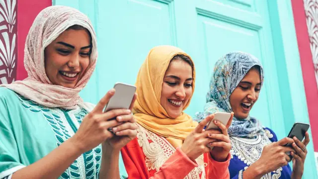 মুসলিম মেয়েরা মোবাইল ফোনে সোশাল মিডিয়া ব্যবহার করছে।