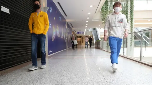 Alışveriş merkezinde maskeyle yürüyenler.