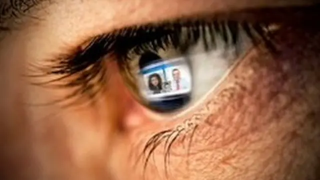 Un écran d'ordinateur montrant une réunion virtuelle se reflète dans l'œil d'une personne