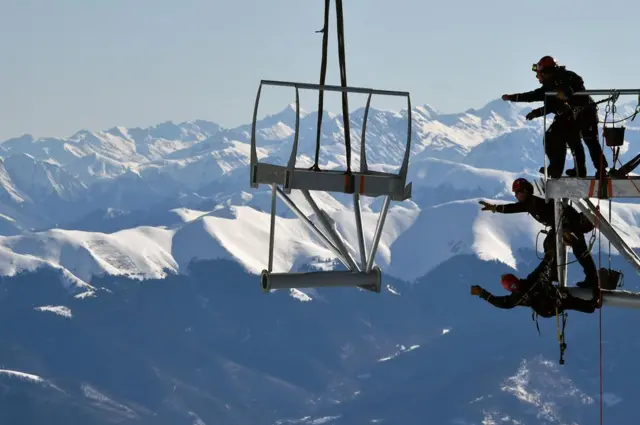 أشخاص على متن منصة حديدية أعلى قمة جبل