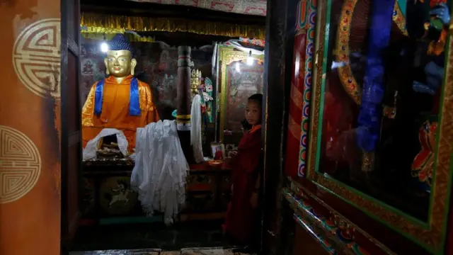 बुद्ध की प्रतिमा के सामने खड़ा एक बौद्ध भिक्षु