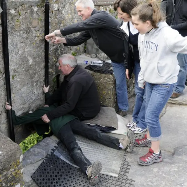 Pengunjung Kastil Blarney dekat Cork, Irlandia, setengah berbaring untuk bisa mencium Batu Blarney, yang menurut legenda, bisa memberikan seseorang 'kemampuan berbicara'.