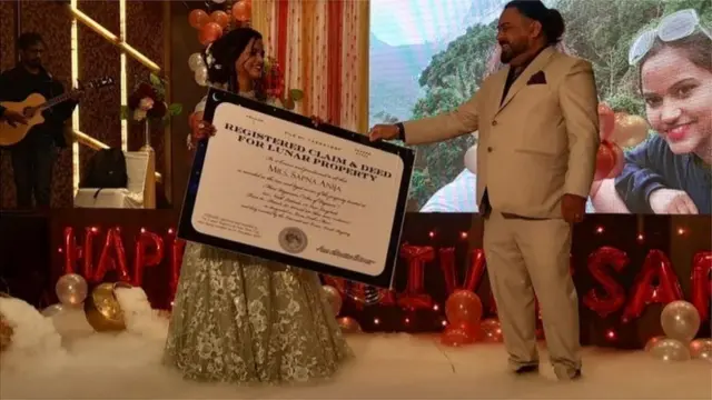 భార్య సప్నాకు చంద్రుడి మీద భూమి రిజిస్ట్రేషన్‌ పత్రాన్ని అందిస్తున్న ధర్మేంద్ర అనీజా