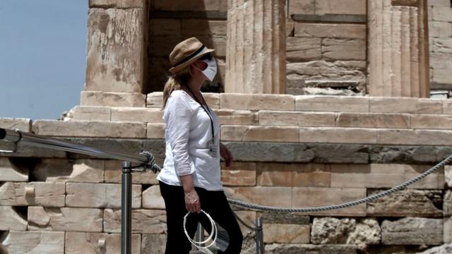 A woman wears a mask at the archaeological site of the Acropolis hill in Athens, 18 May 2020