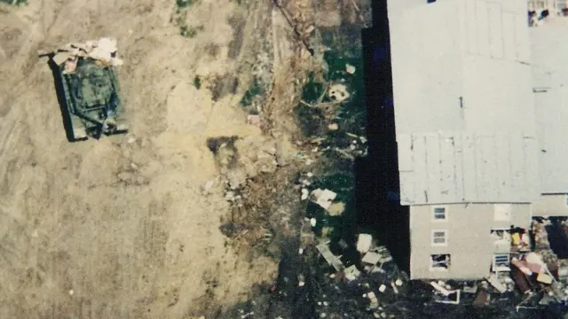 Фотография сверху, танк у стены здания