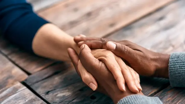 Cropped shot of two unrecognizable people holding hands, comforting each other