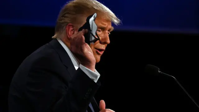 Donald Trump sosteniendo una mascarilla.