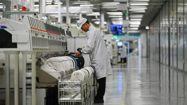An employee works on a mobile phone production line at a Huawei production base during a media tour in Dongguan,