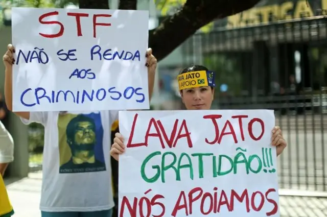 Personas protestas con carteles en contra de la corrupción en Brasil.
