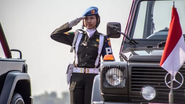 Jovem mulher usando uniforme militar da Indonésia faz continência