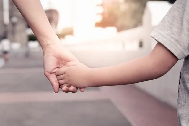 Una madre y un niño tomados de la mano