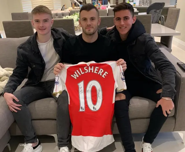 Jake et Cam avec Jack Wilshire tenant une chemise signée.