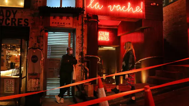 晚六時後，兩位市民在已停止堂食的餐廳外等外賣。