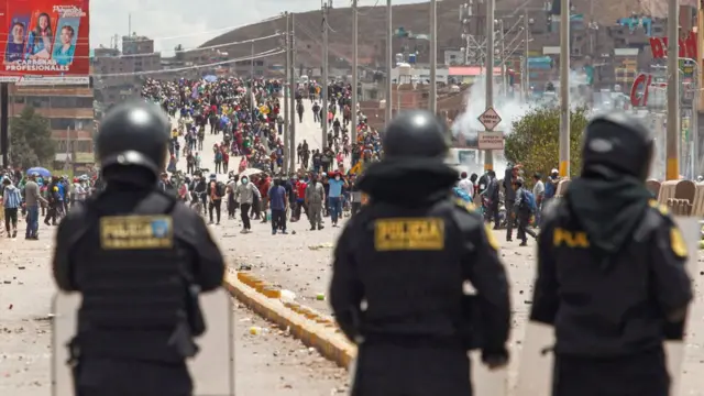 Tres policías observan a los manifestantes que se les acercan en Juliaca.