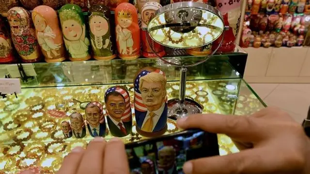 A man takes pictures of traditional Russian wooden nesting dolls, Matryoshka dolls, depicting US Republican presidential nominee Donald Trum
