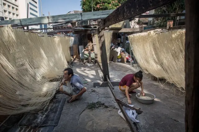 Two Thai men making traditional Chinese style noodles in a Bangkok market
