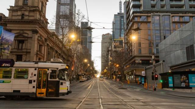 A tram crosses a deserted street in central Melbourne during lockdown
