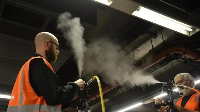 Участники эксперимента распыляют частицы на платформе линии 4/5/6 на одной из нью-йоркских станций