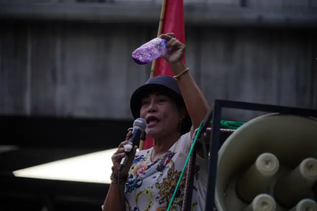 ผู้ประท้วงชูขวดน้ำมีของเหลวสีม่วง