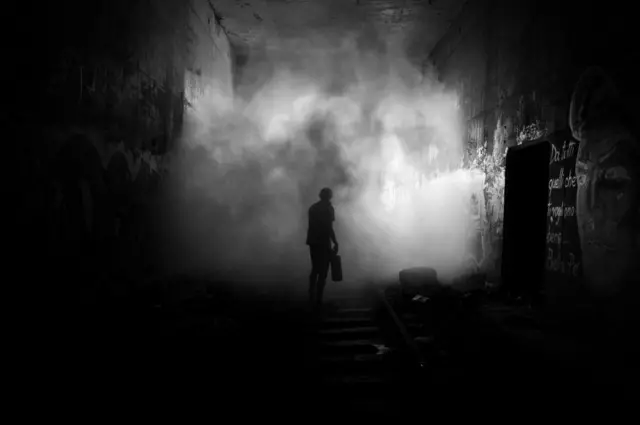 Уличный художник идет по шпалам в темноте