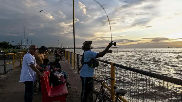 Personas pescando en un muelle de Georgetown, Guyana.