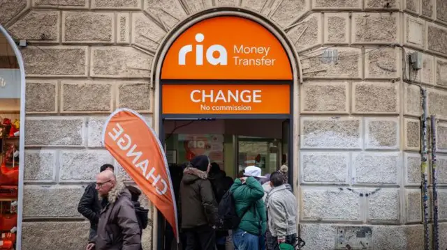 Ludzie ustawiają się w kolejce przy punkcie Ria Money Transfer.
