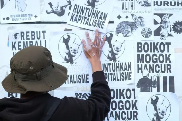 Mahasiswa menempelkan sejumlah poster di tiang penyangga baliho saat mengikuti aksi Hari Buruh Internasional di Bundaran Digulis, Pontianak, Kalimantan Barat, Kamis (01/05). Mereka menyuarakan sejumlah isu, seperti pengabaian hak buruh di Kalbar, perampasan lahan, penolakan militerisme, kerusakan lingkungan, serta kritik terhadap investasi yang dinilai belum berdampak signifikan pada perekonomian warga. 
