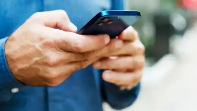 Uma mão digitando em um celular