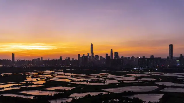 2021年10月11日星期一，黄昏时分，香港落马洲地区农田外，深圳的建筑群在地平线上若隐若现。