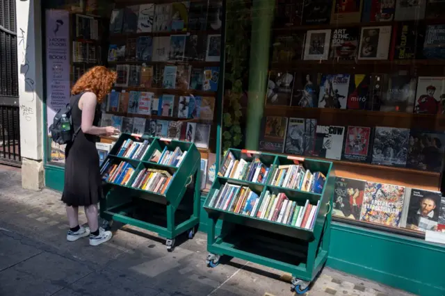 Woman browses outside a second hand book shop window on Charing Cross Road on 11th July 2022 in London, United Kingdom.